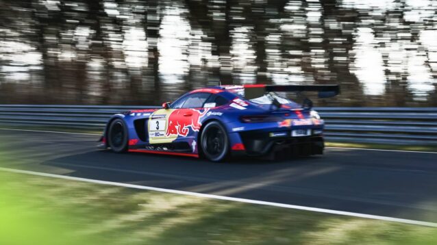 A rear-facing shot of Max Verstappen on track in a Red Bull-branded Mercedes-AMG GT3 at the Nurburgring with trees in the background
