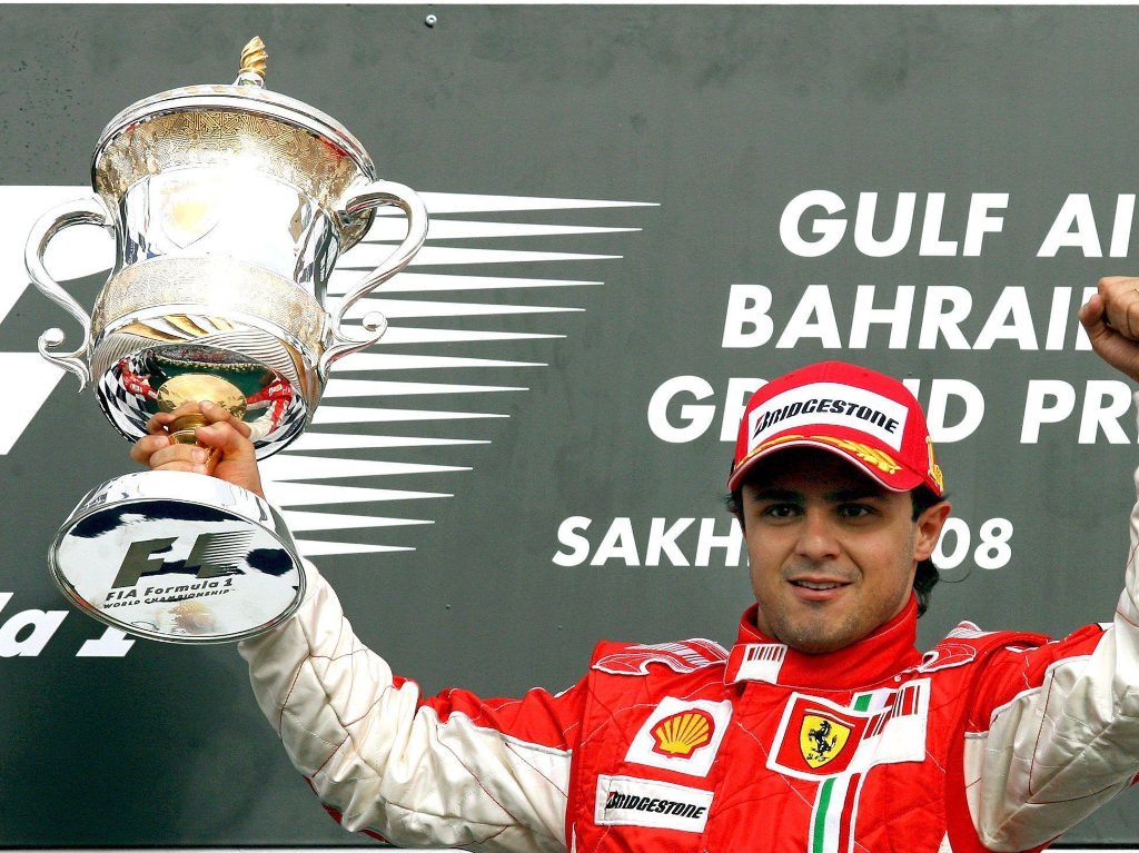 Kimi Raikkonen raises his winner's trophy on the podium as Felipe