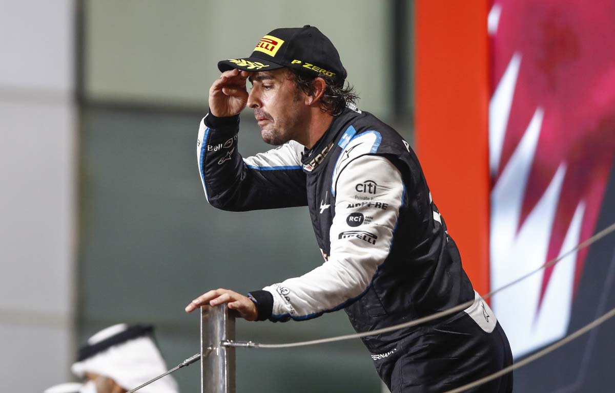 Fernando Alonso peers out over the podium. Qatar November 2021.