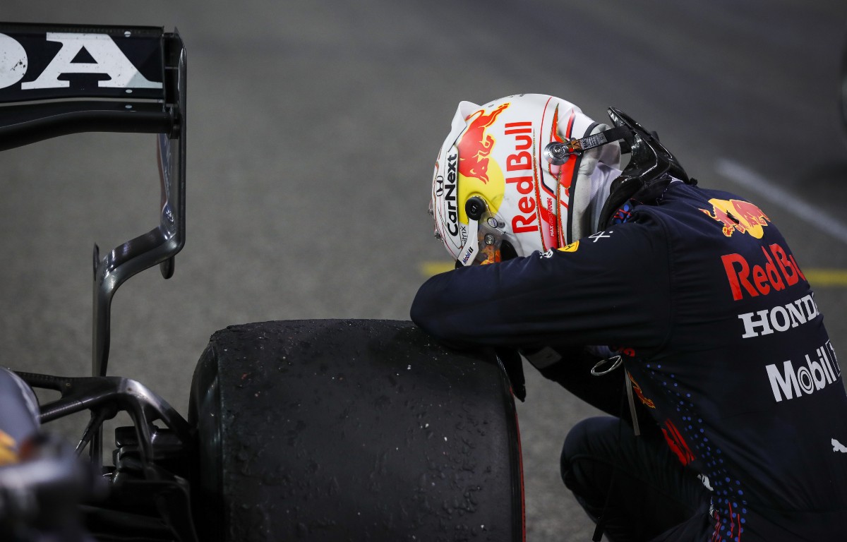 Max Verstappen kneels by his Red Bull. Abu Dhabi, December 2021.