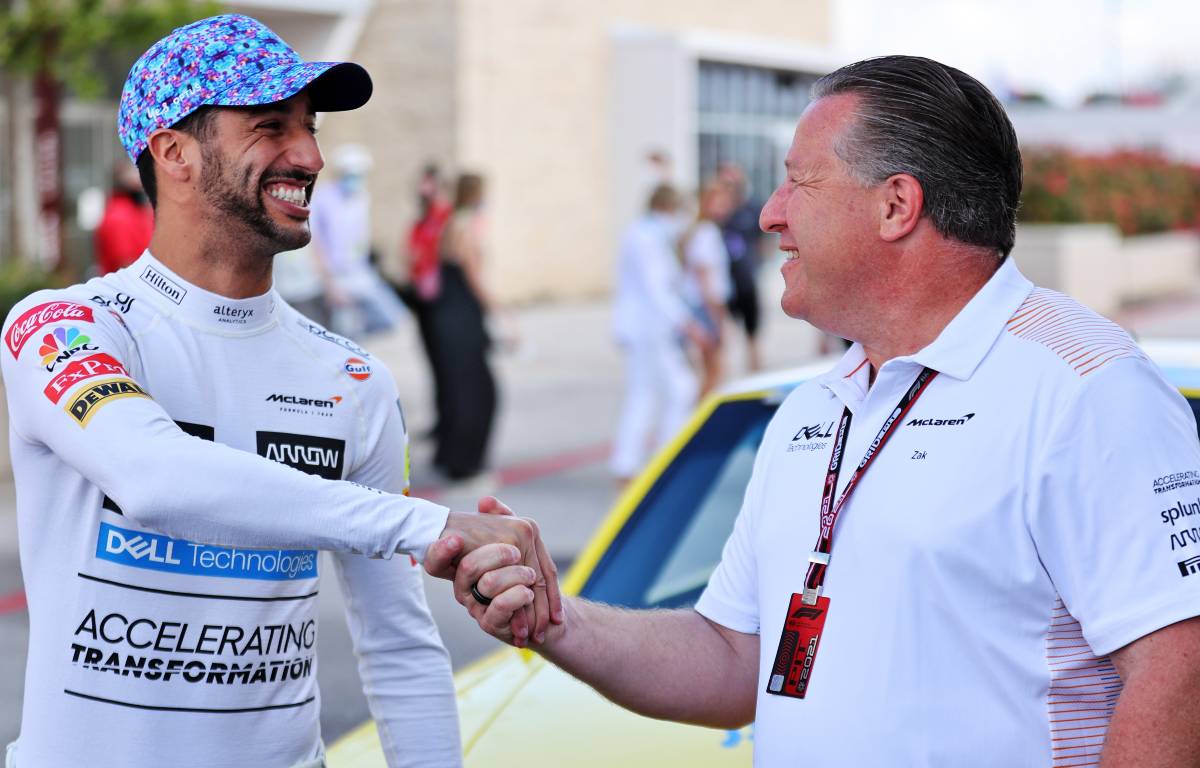 Daniel Ricciardo and Zak Brown shake hands in front of Dale Earnhardt's NASCAR. Austin October 2021.