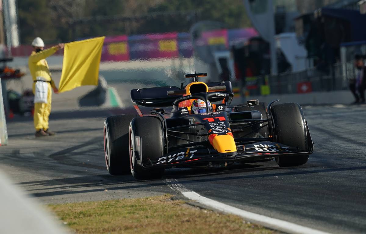 Sergio Perez in the RB18 with a yellow flag behind. Spain, February 2022.