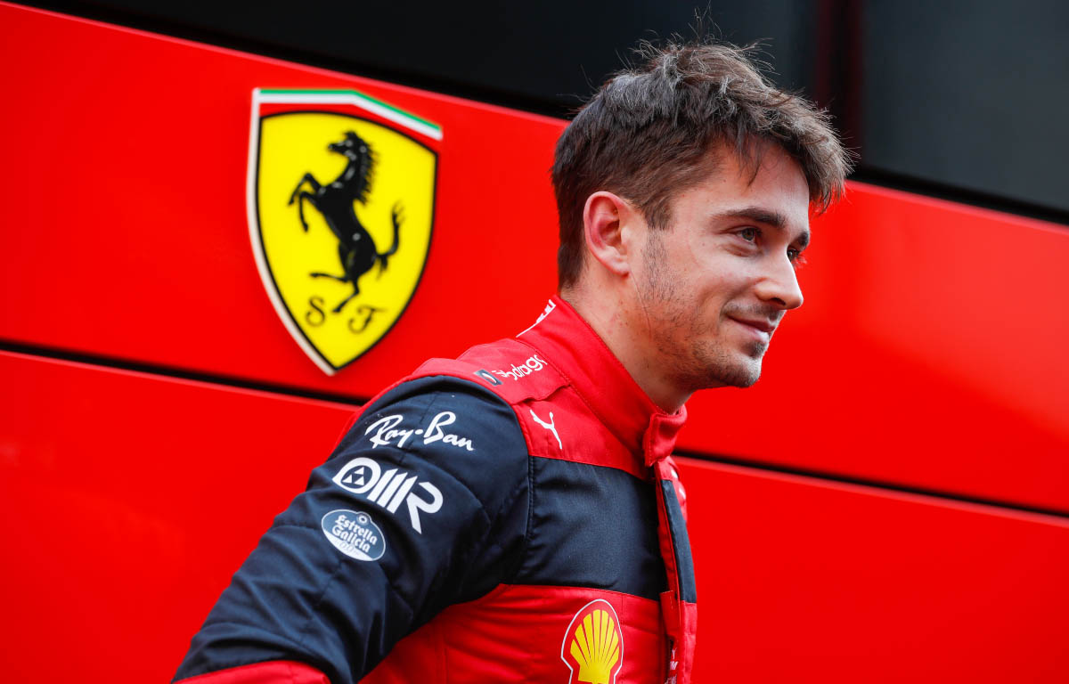 Charles Leclerc stood with a Ferrari badge behind him. Barcelona February 2022.
