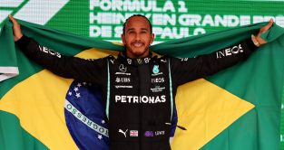 刘易斯·汉密尔顿在领奖台上举着巴西国旗庆祝。Interlagos 2021年11月。
