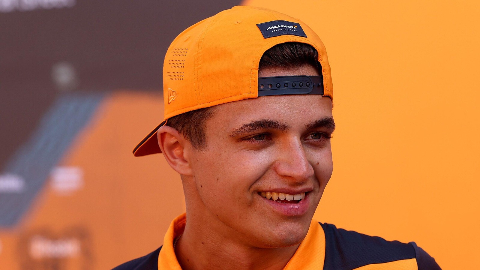 Lando Norris smiles whilst wearing a hat. Barcelona, May 2022.