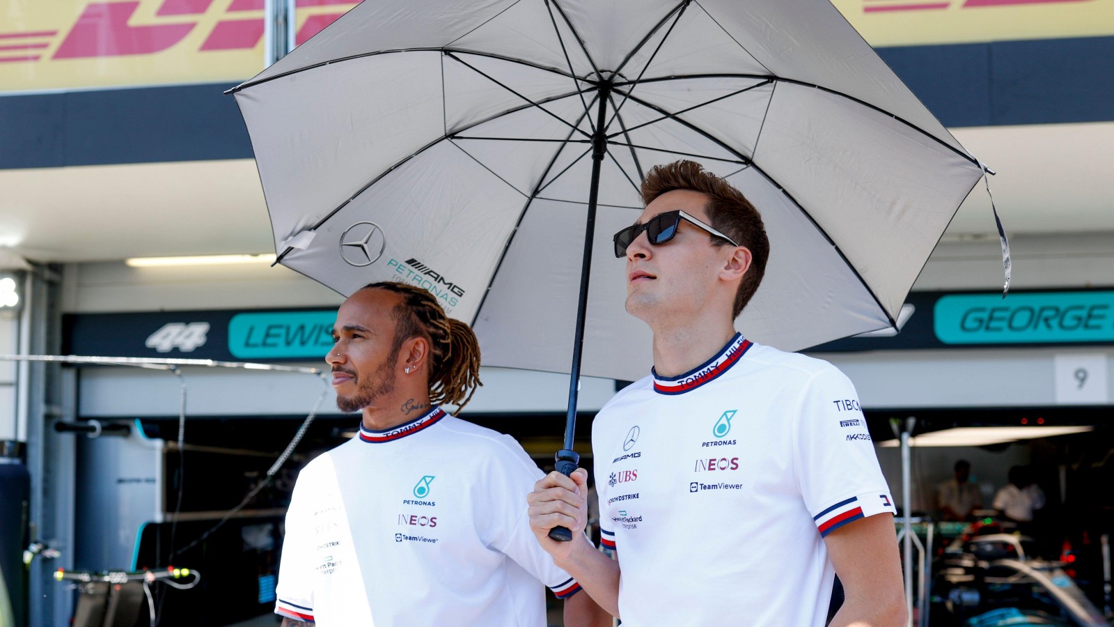 Mercedes team-mates Lewis Hamilton and George Russell standing under an umbrella. Azerbaijan, June 2022.