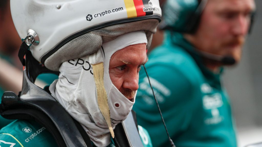 Sebastian Vettel looking serious with his helmet perched on his head. Monaco May 2022