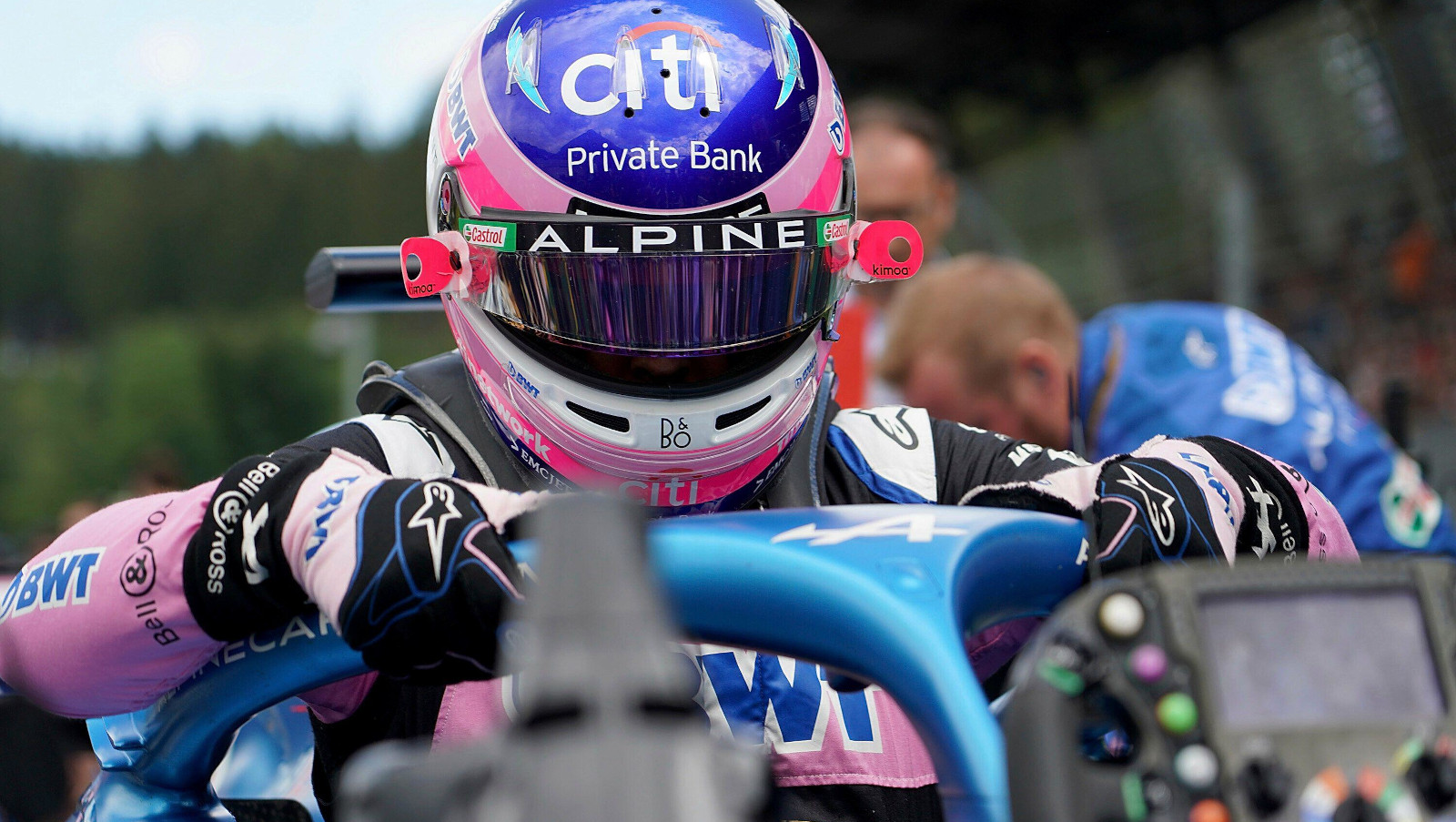 Fernando Alonso climbs into his car on the grid, steering wheel on the car's nose. Austria July 2022