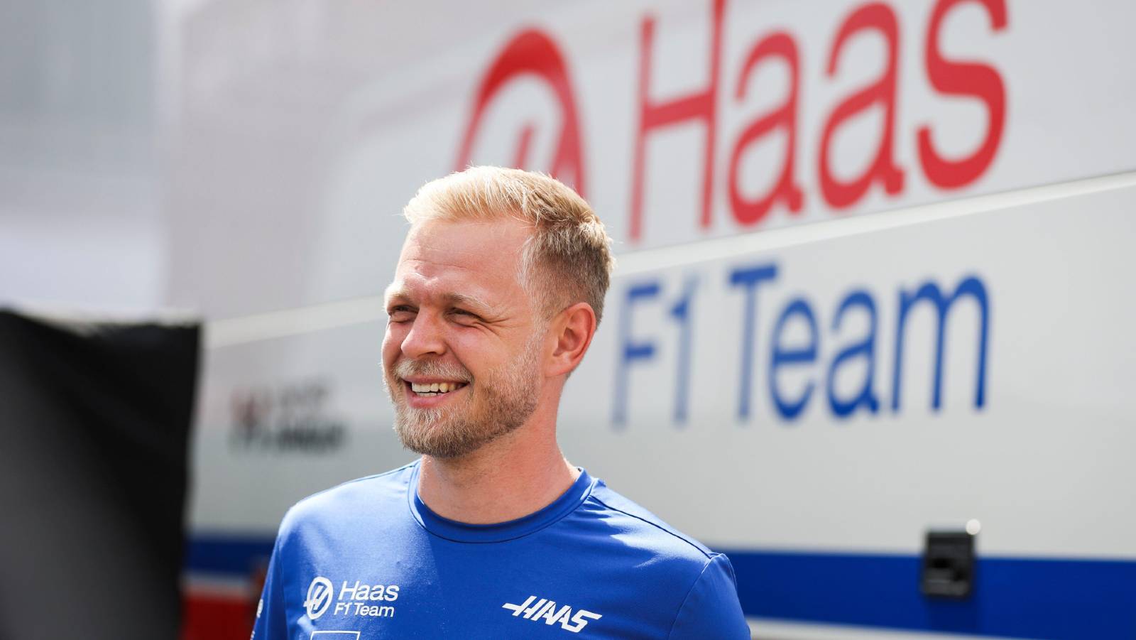 Kevin Magnussen smiling next to a Haas truck. Hungaroring July 2022.