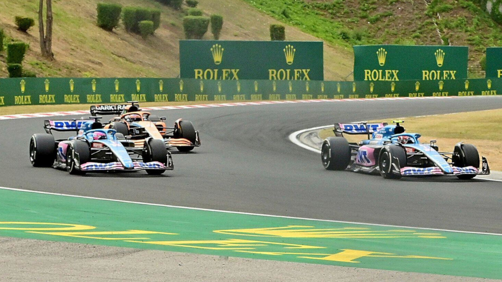 Daniel Ricciardo, McLaren, racing the two Alpines. Hungary July 2022