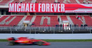 Charles Leclerc drives past a Michael Schumacher sign. Barcelona, Spain, February 2019