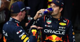Max Verstappen explains to Sergio Perez while the race winner drinks a Red Bull. Saudi Arabia March 2023