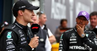 George Russell gives an interview as Lewis Hamilton watches on. Australia April 2023