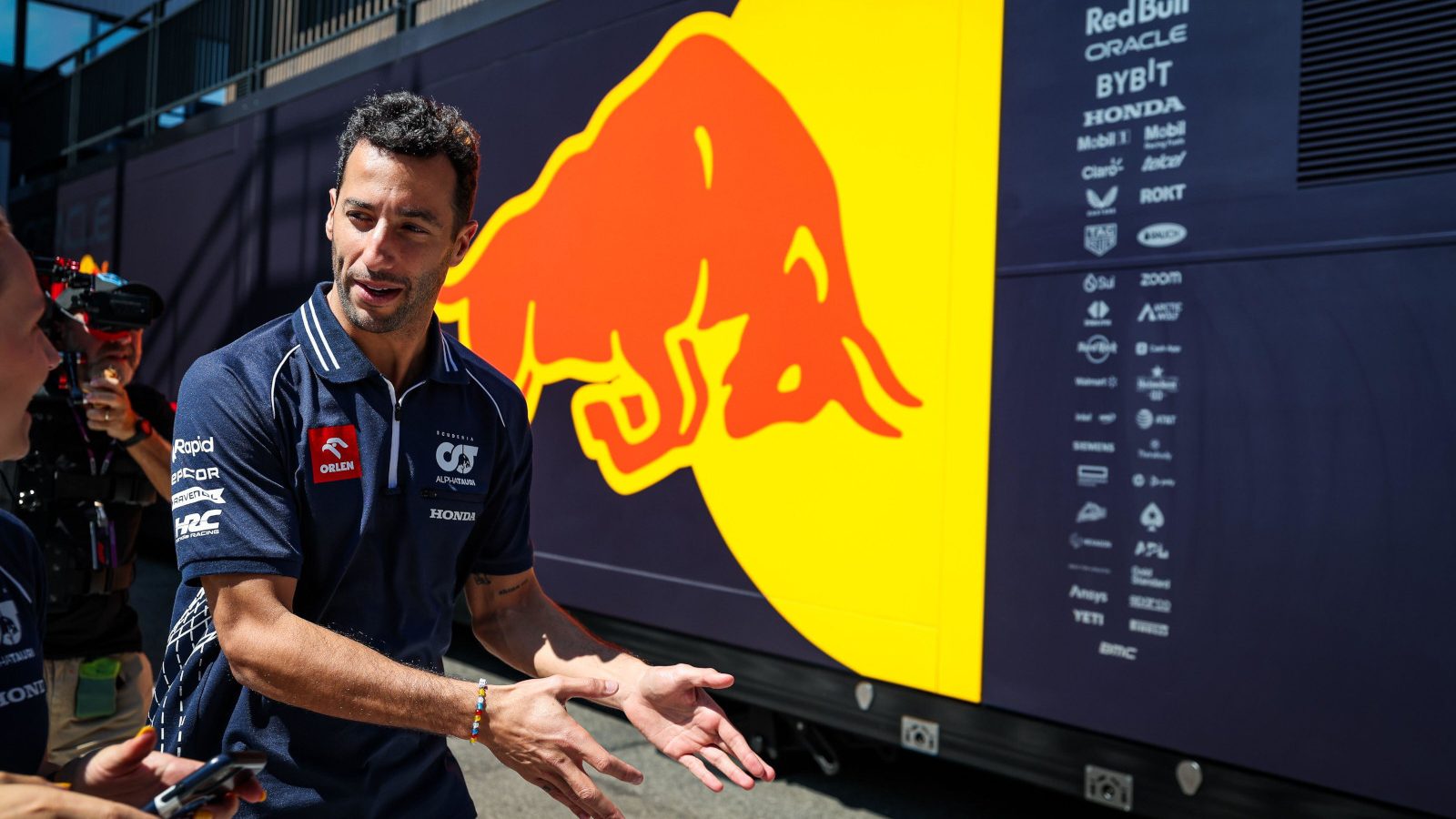 Daniel Ricciardo gesturing toward the Red Bull garage of Max Verstappen. Hungary July 2023