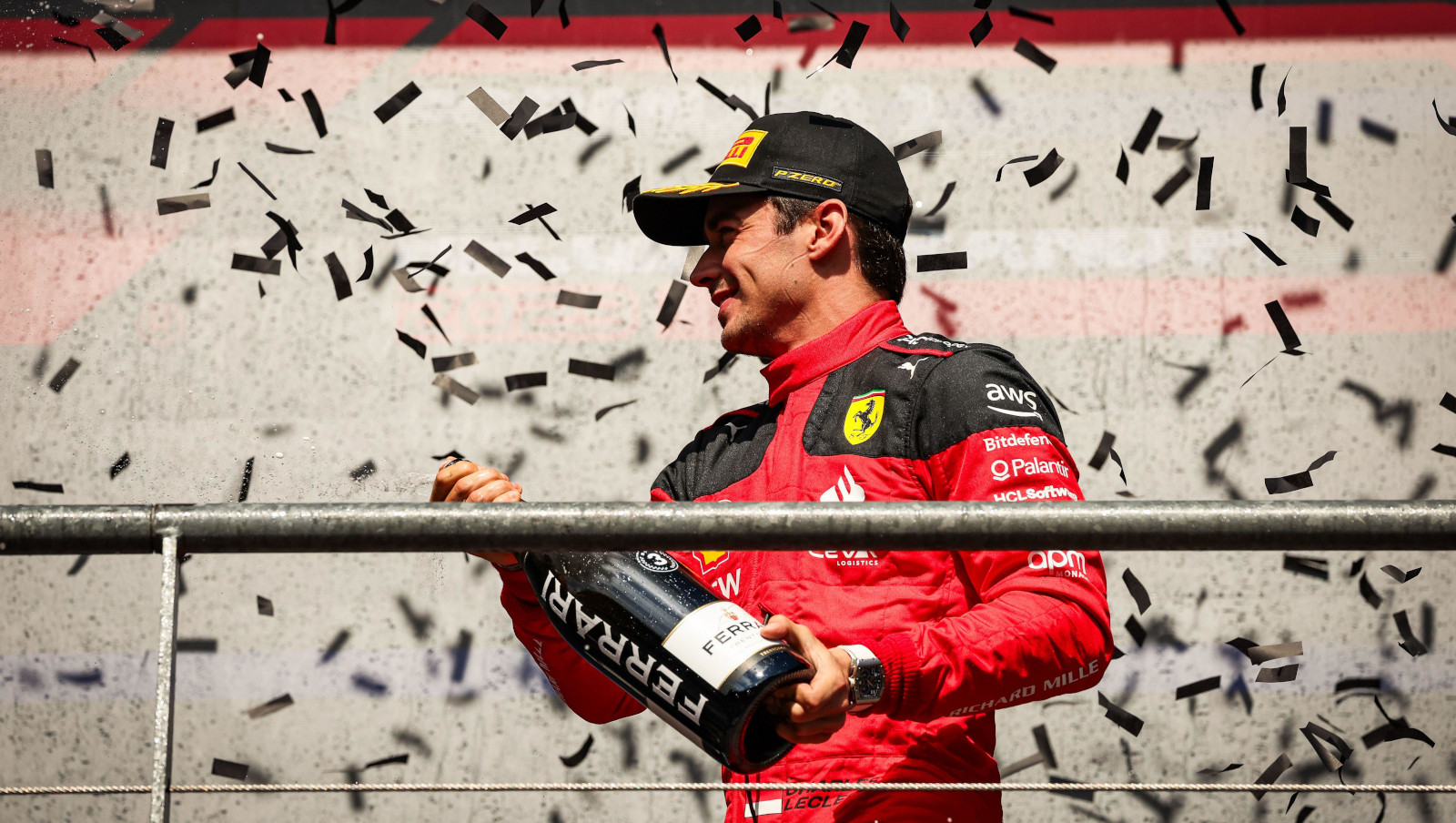 Charles Leclerc smiling while spraying Ferrari champagne on the podium at the Belgian Grand Prix