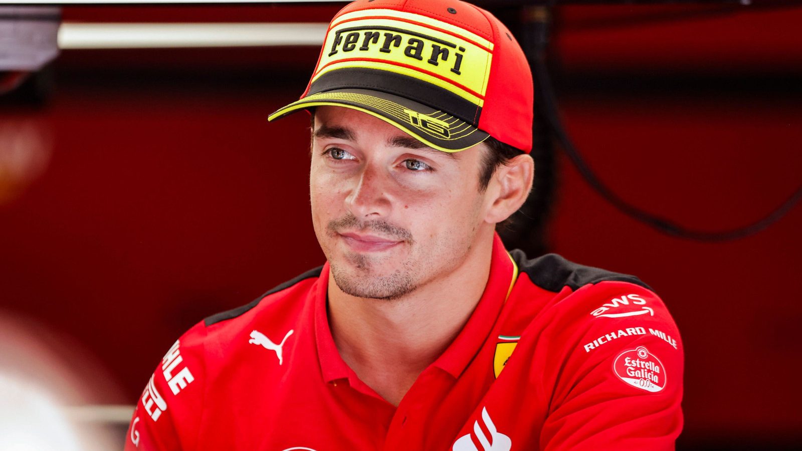 Charles Leclerc smiling in the Ferrari garage as he prepares for the Italian Grand Prix weekend.