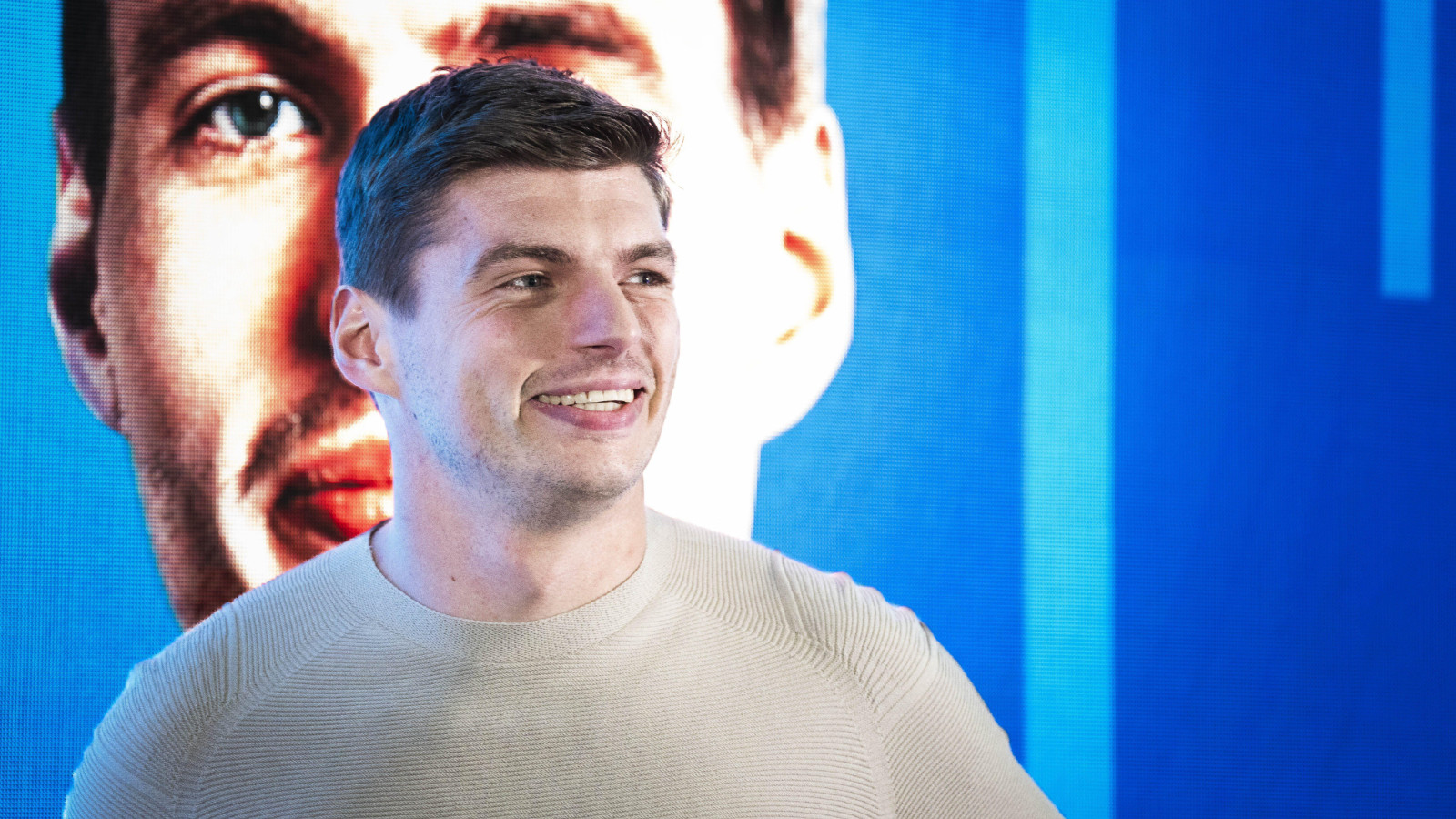 Max Verstappen, dressed casually, smiles during an off-season event after the 2023 F1 championship.