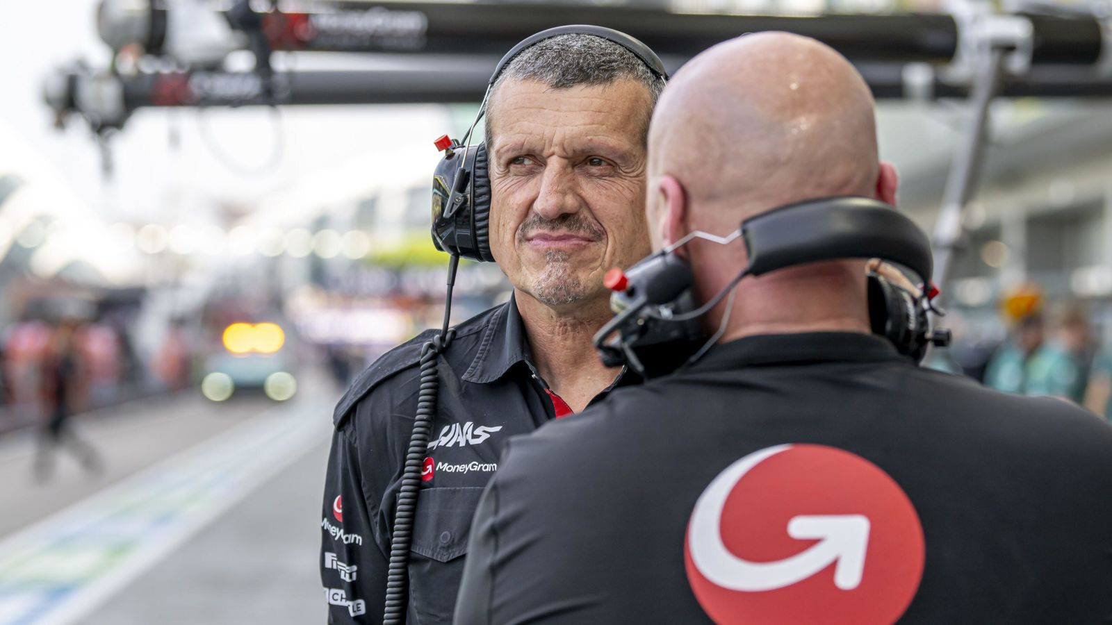 Former Haas team boss Guenther Steiner talks to a crew member in the pit lane.