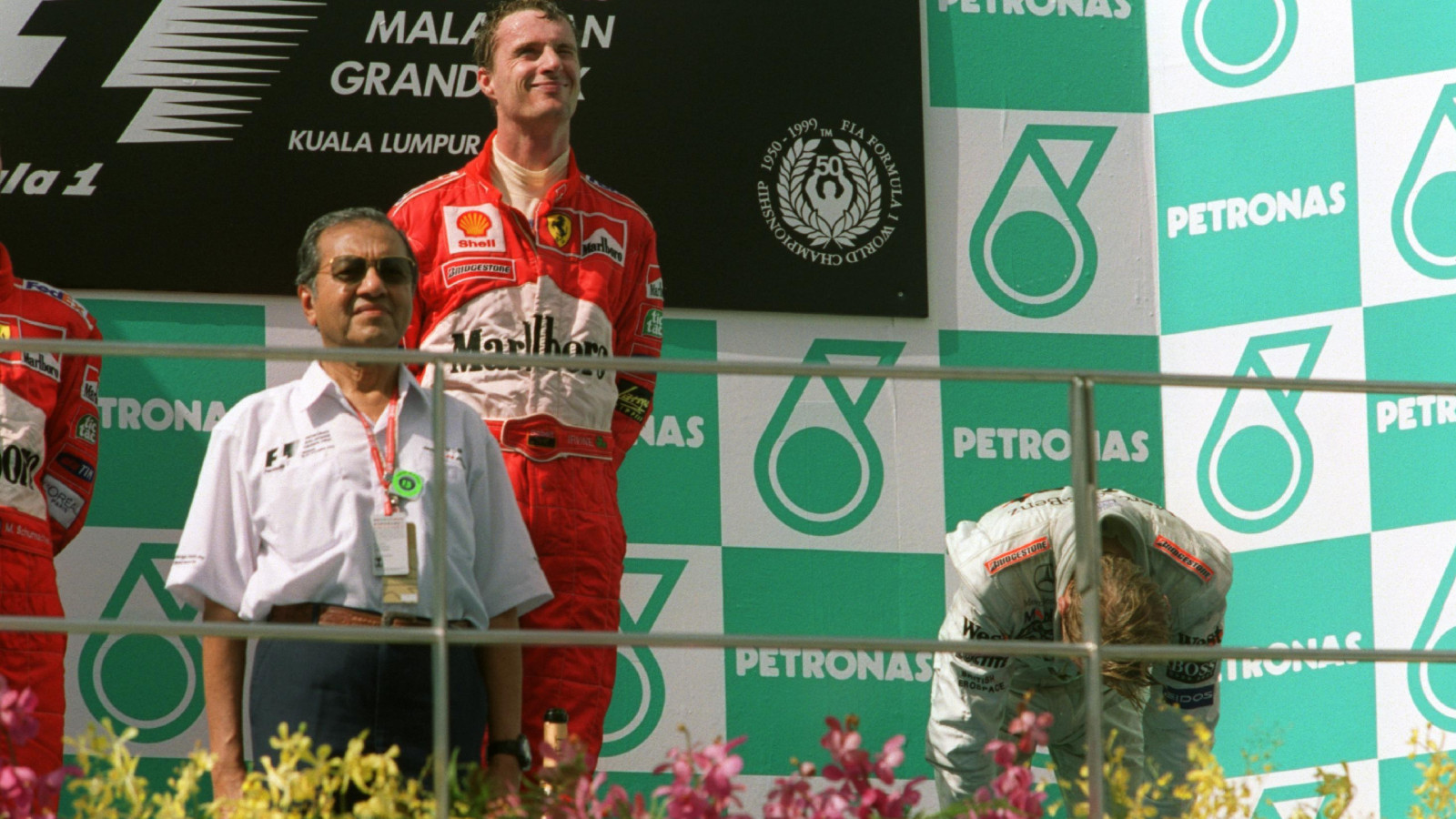 McLaren's Mika Hakkinen doubles over in exhaustion after the 1999 Malaysian Grand Prix.