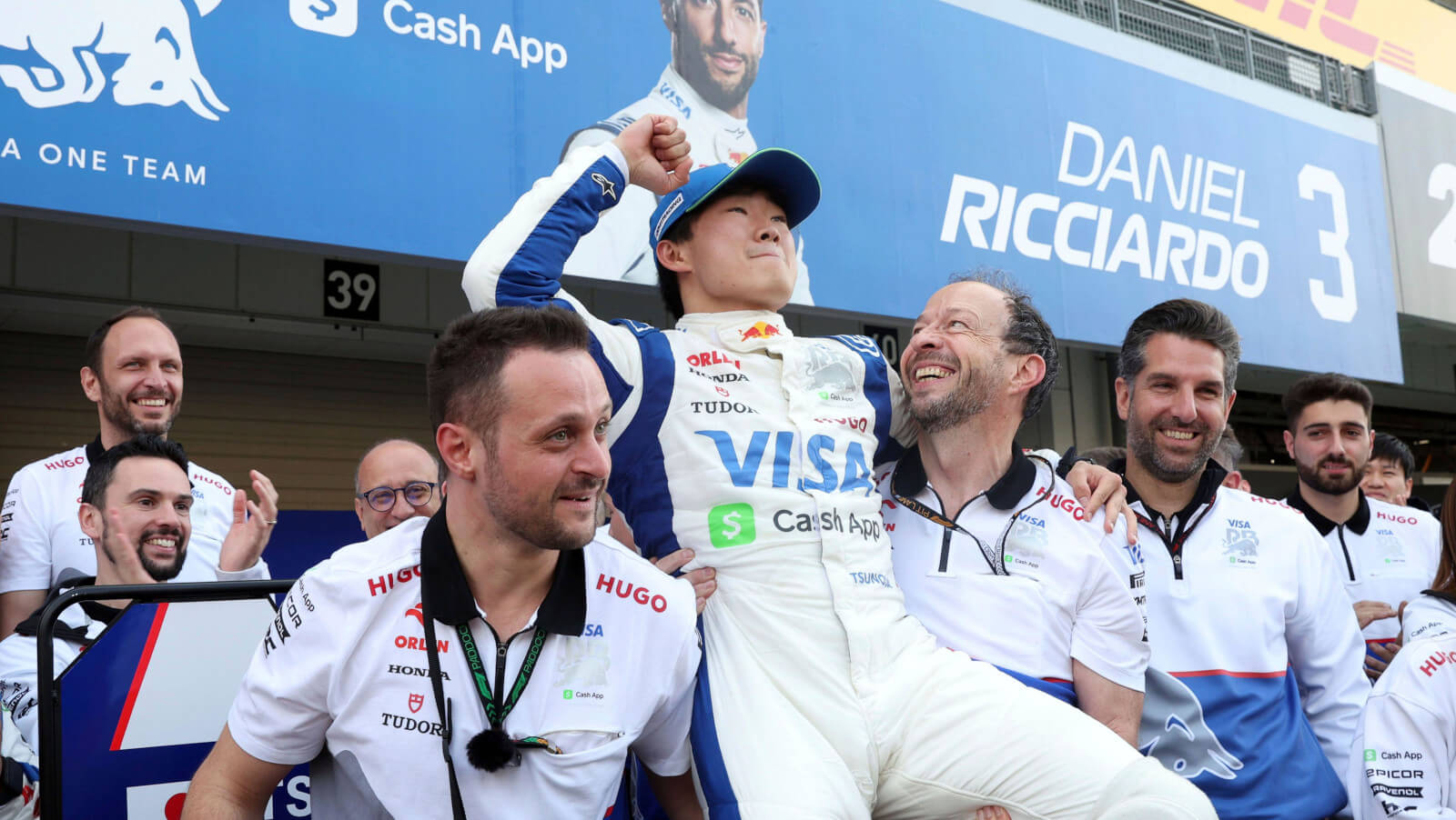 Yuki Tsunoda celebrates in front of Daniel Ricciardo's garage