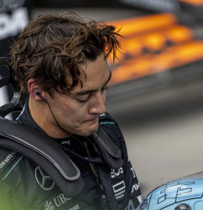George Russell looks downbeat in parc ferme as he places his helmet on a table