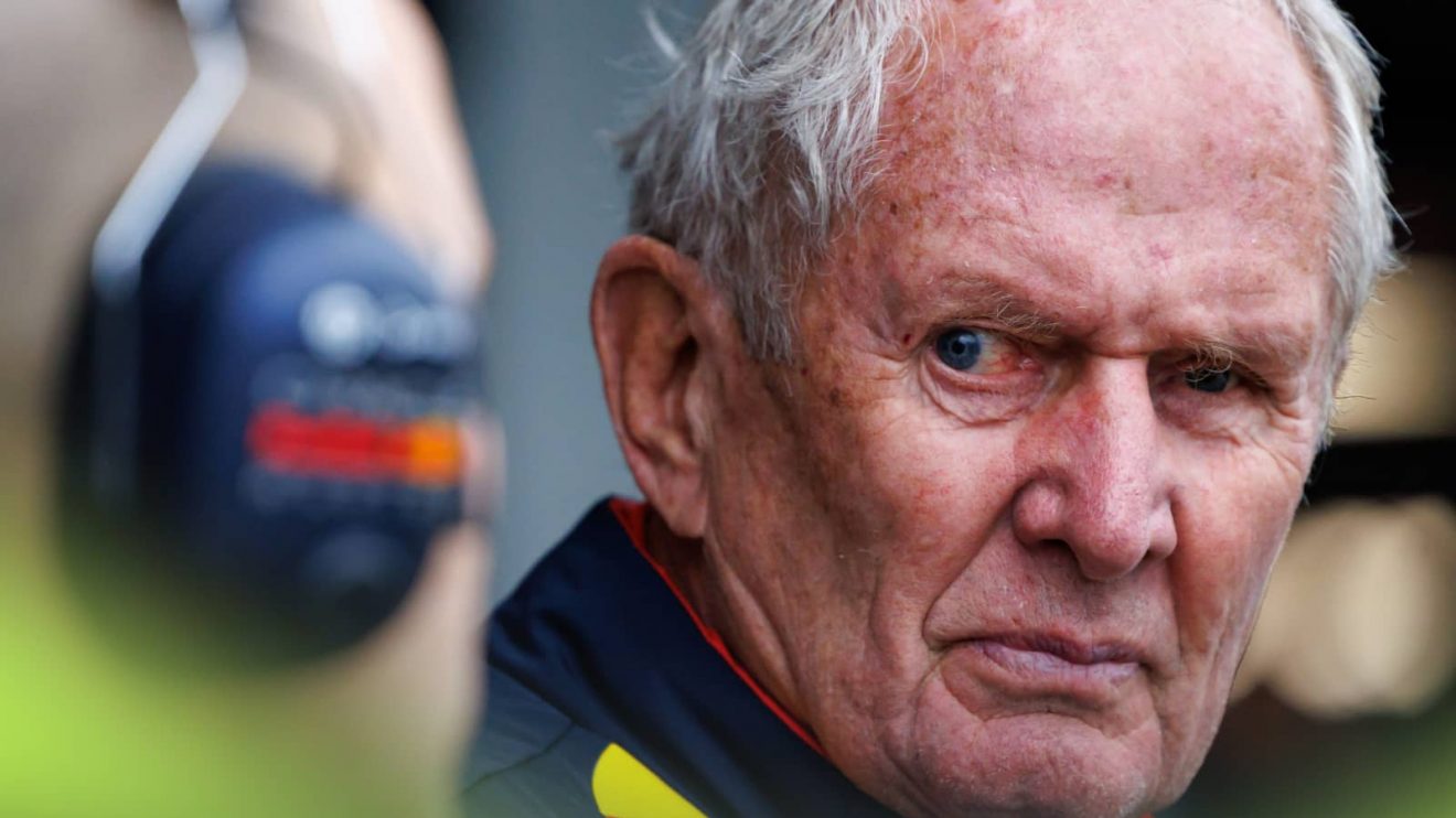 A close-up shot of Helmut Marko glancing down the pit lane with a Red Bull mechanic alongside him
