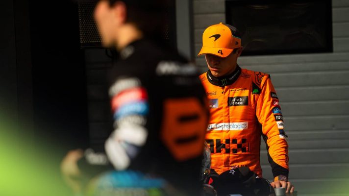 Lando Norris looks downbeat as a blurry Oscar Piastri passes in the foreground