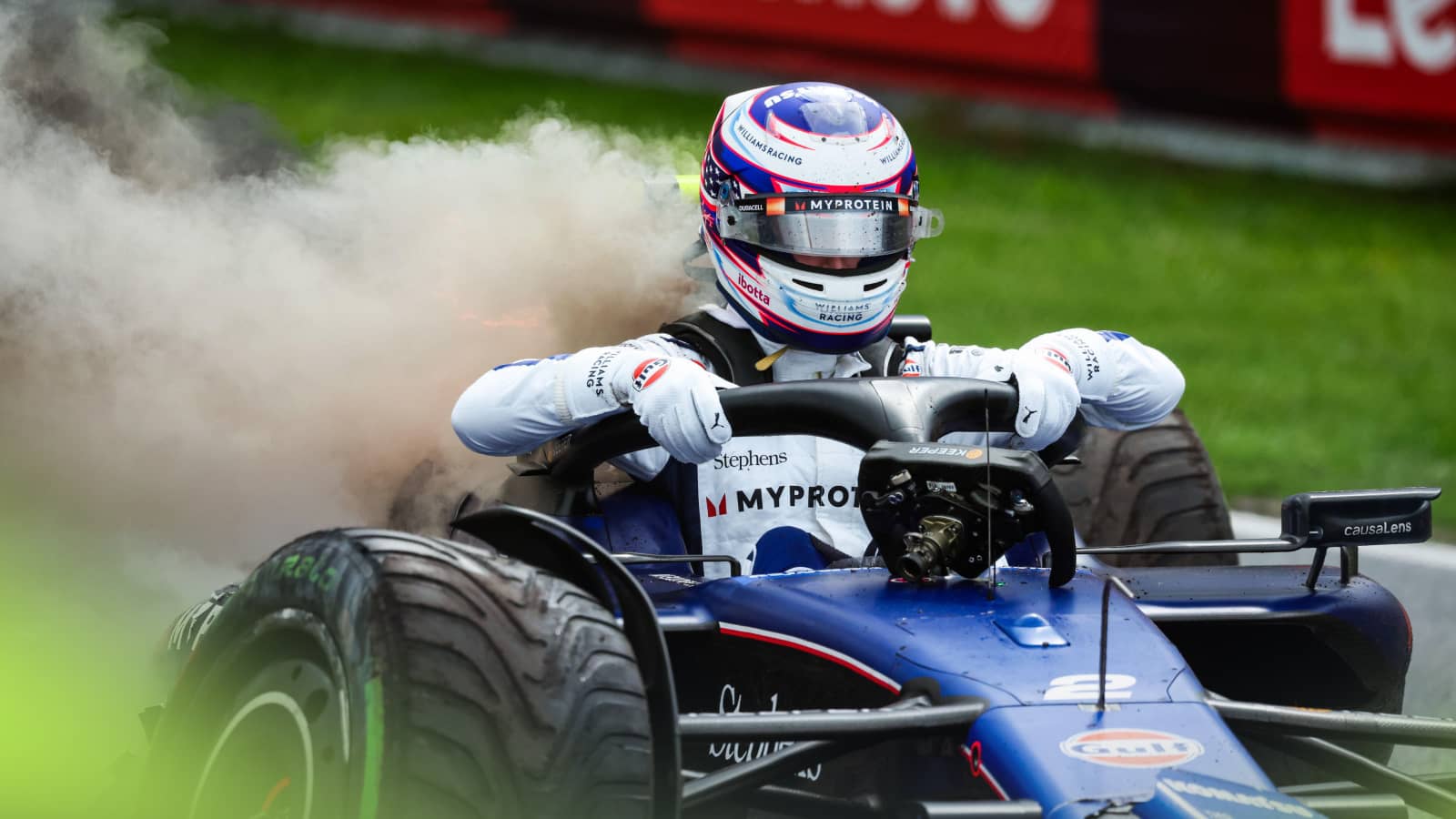 Logan Sargeant grips on to the halo as he hauls himself out of his smoky Williams following his practice crash at Zandvoort