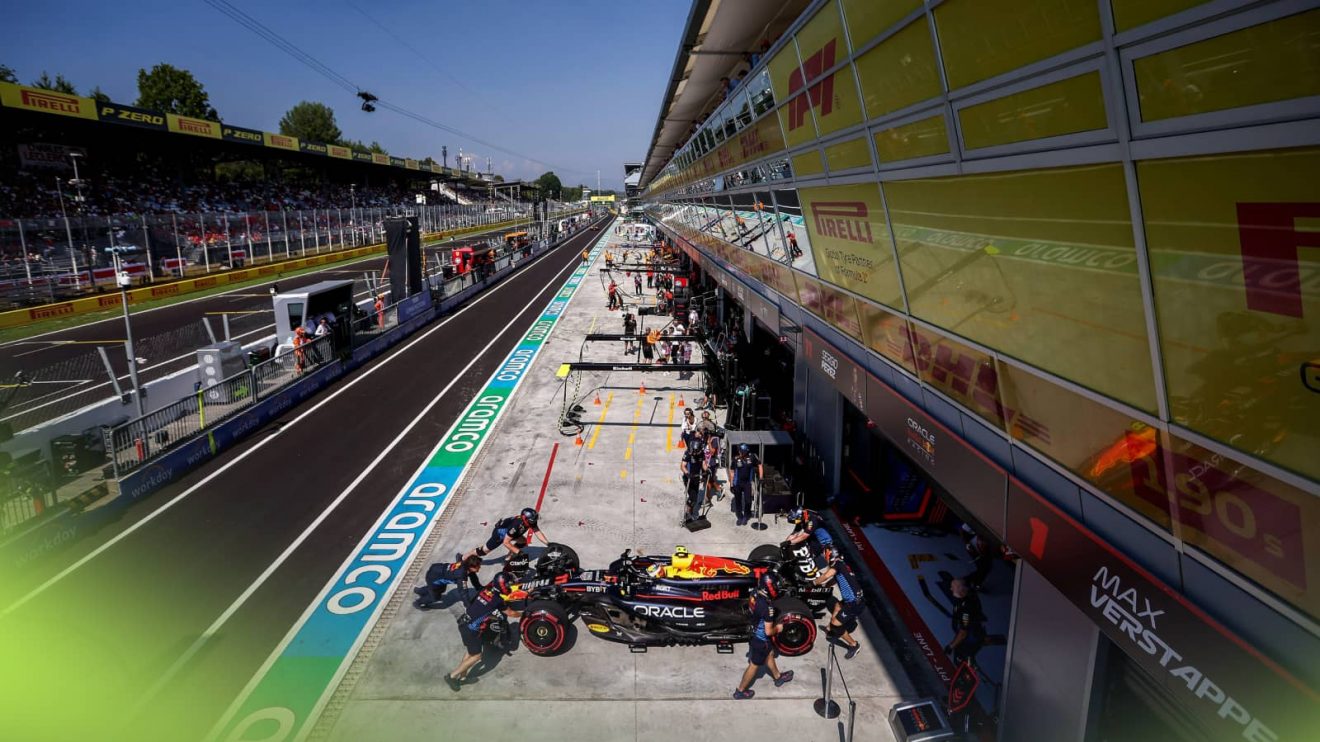 Sergio Perez is pushed back into the garage by Red Bull mechanics with a view of Monza's pit straight in the background