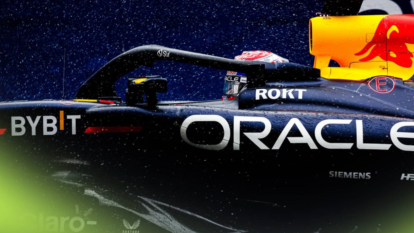 A side-profile shot of rain falling on Max Verstappen and the Red Bull RB20 on track