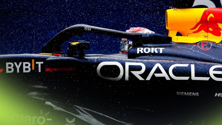 A side-profile shot of rain falling on Max Verstappen and the Red Bull RB20 on track