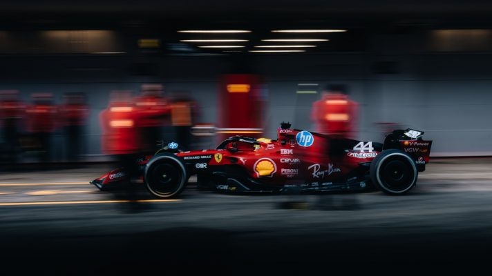 A side-profile shot of Lewis Hamilton pulling into the Ferrari pit box with a blurred effect on the pit crew