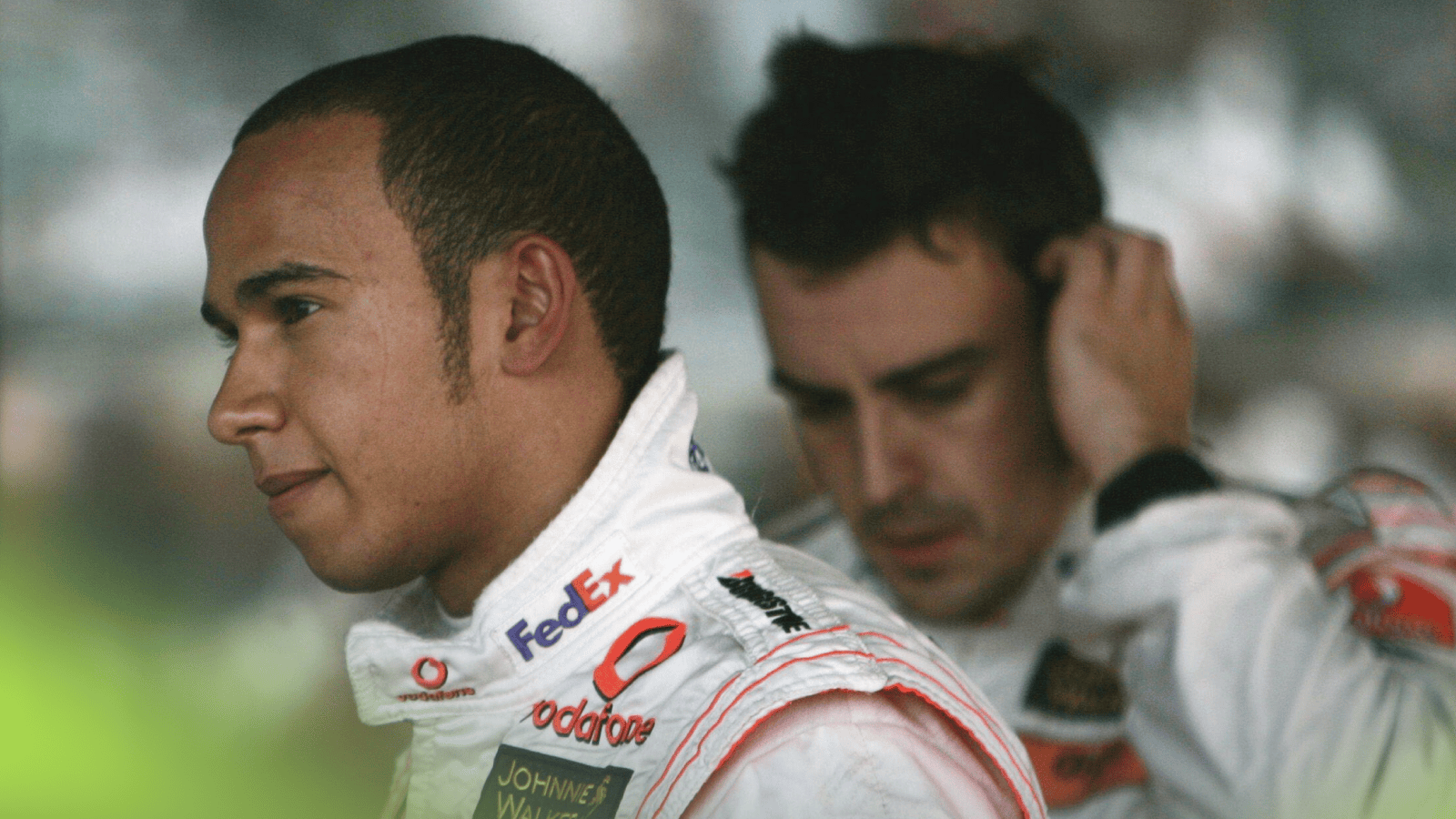 Lewis Hamilton looks on in parc ferme with Fernando Alonso looking frustrated in the background