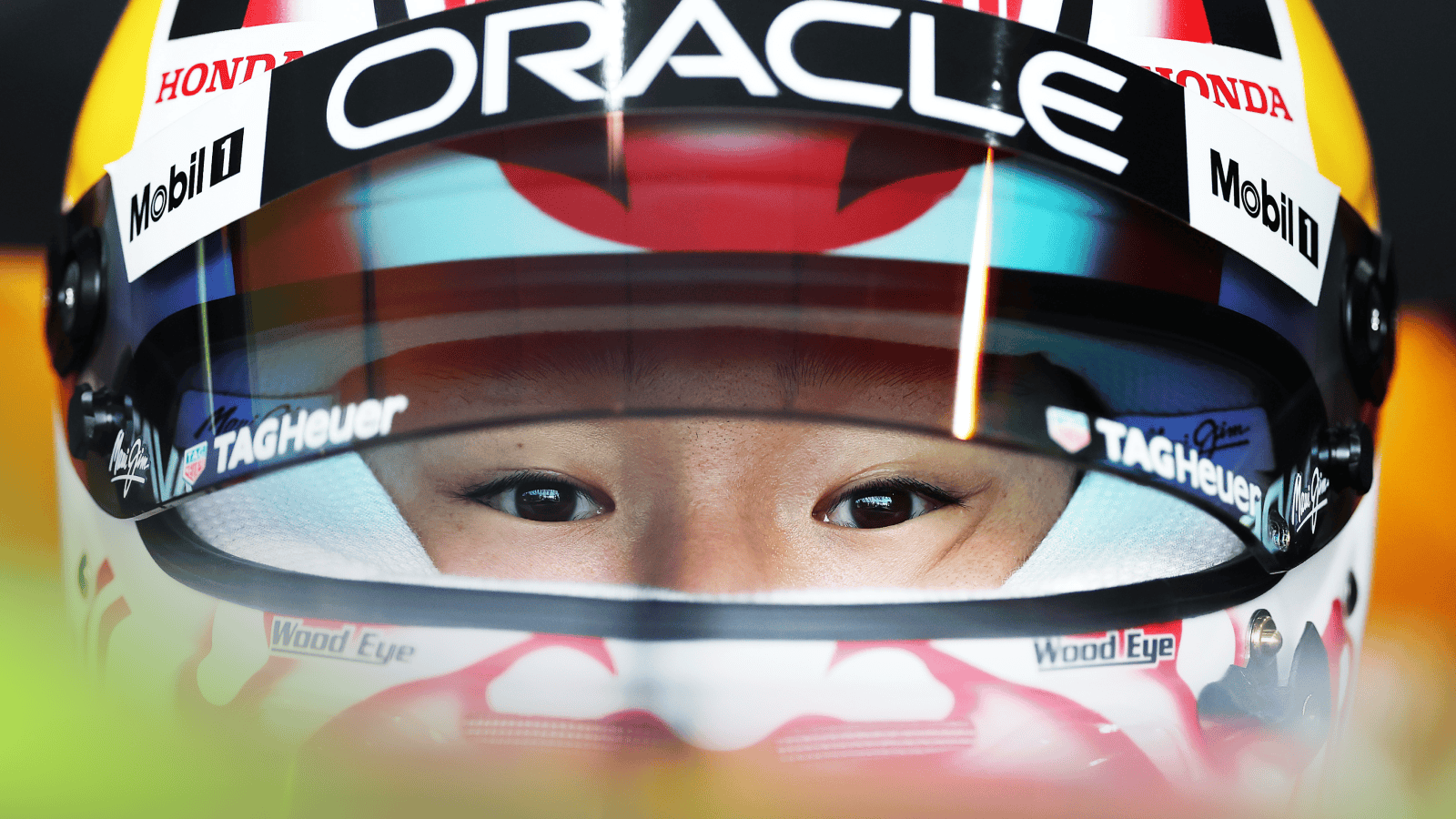 A close-up shot of Yuki Tsunoda with the visor of his helmet open