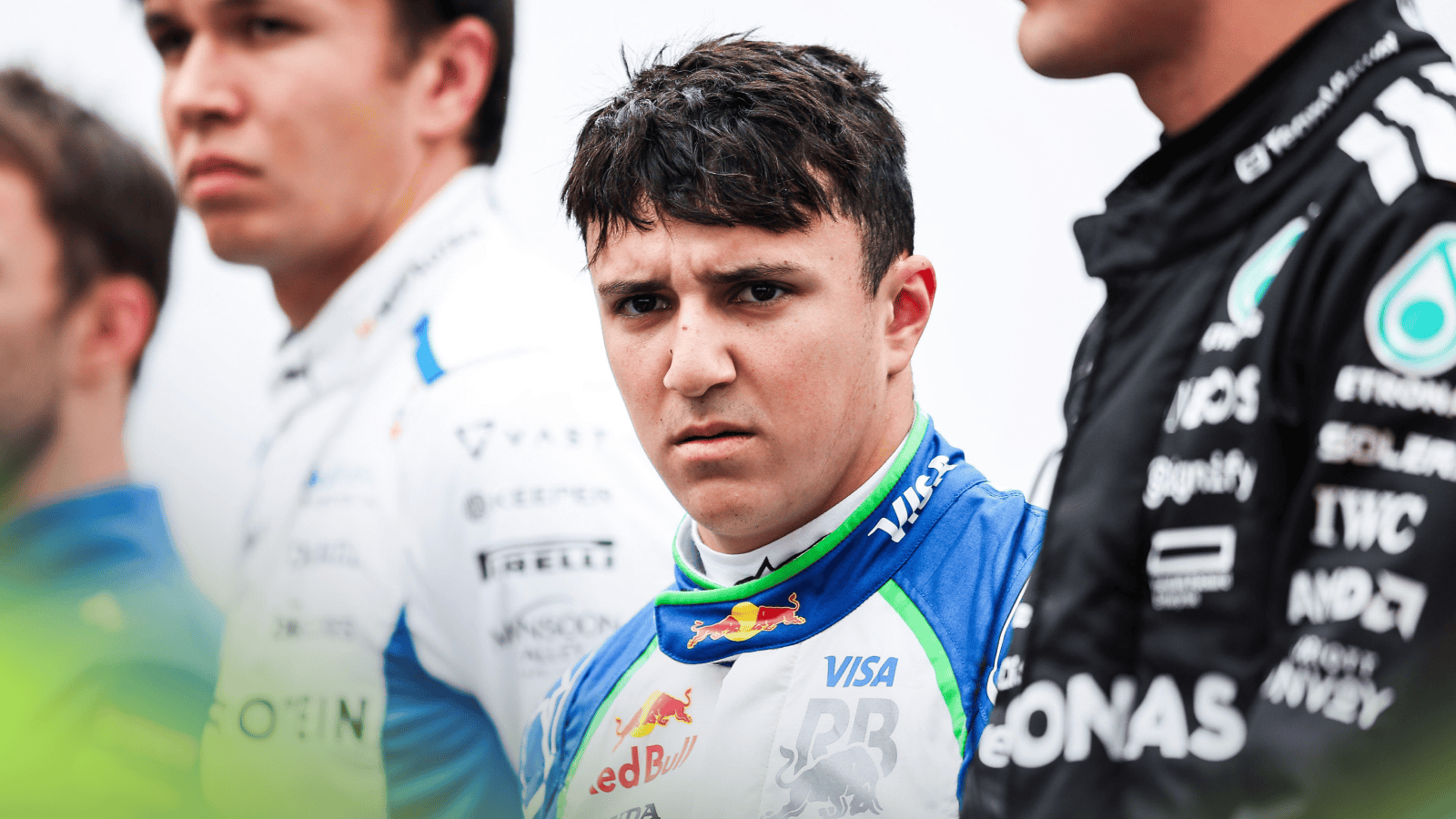 Isack Hadjar scowls at the camera as he lines up alongside Alex Albon and George Russell for the national anthem at Suzuka