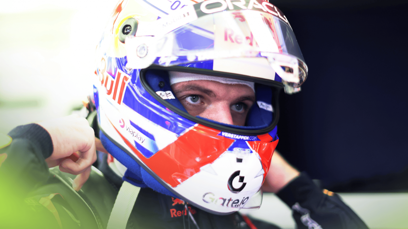 Max Verstappen's eyes visible through the open visor of his helmet in the Red Bull garage
