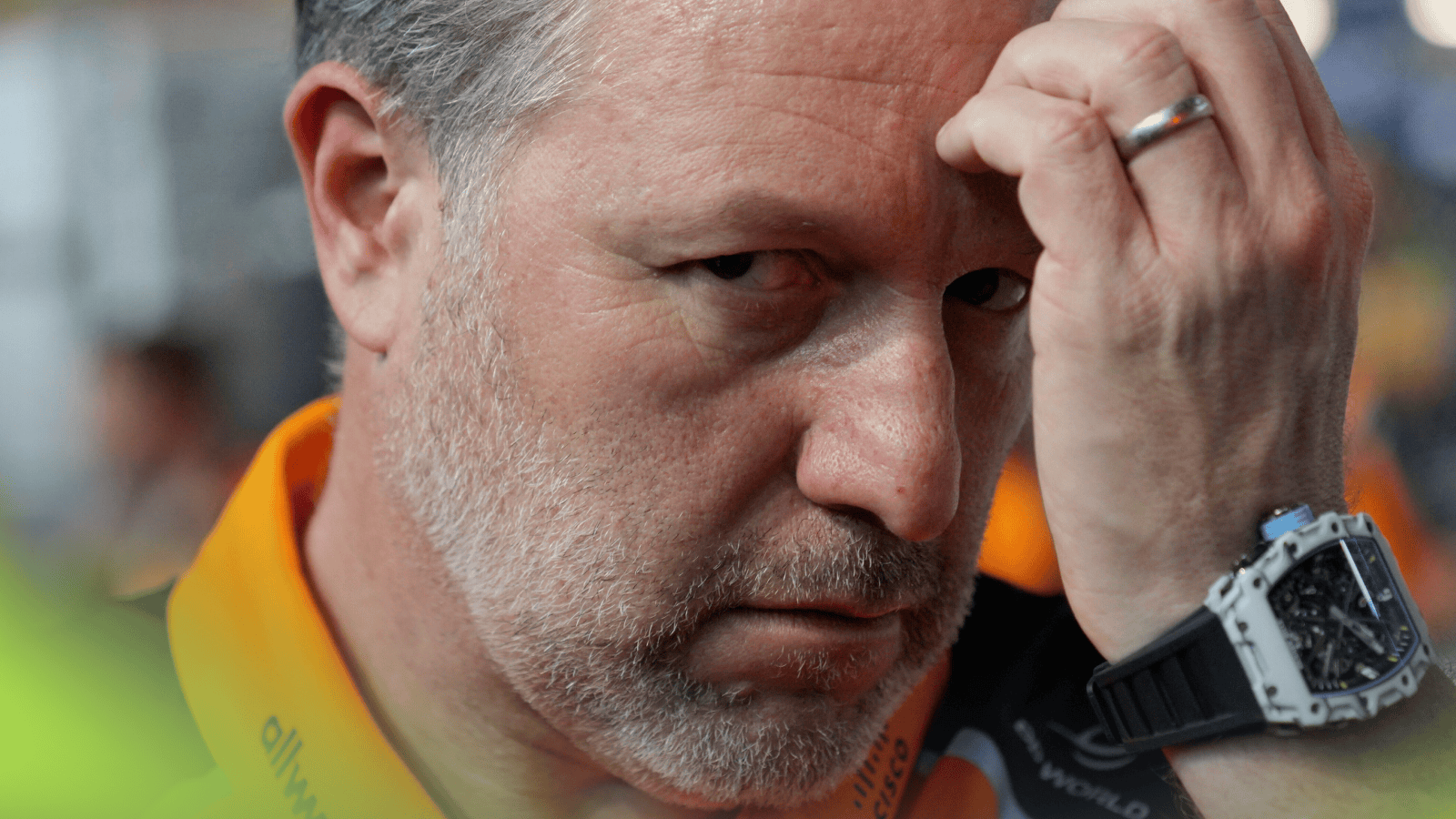 A close-up shot of Zak Brown eyeing the camera as he rubs his forehead on the grid in Jeddah