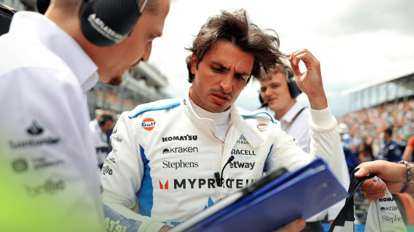 Carlos Sainz looks at a folder held by his Williams engineer on the grid in Miami