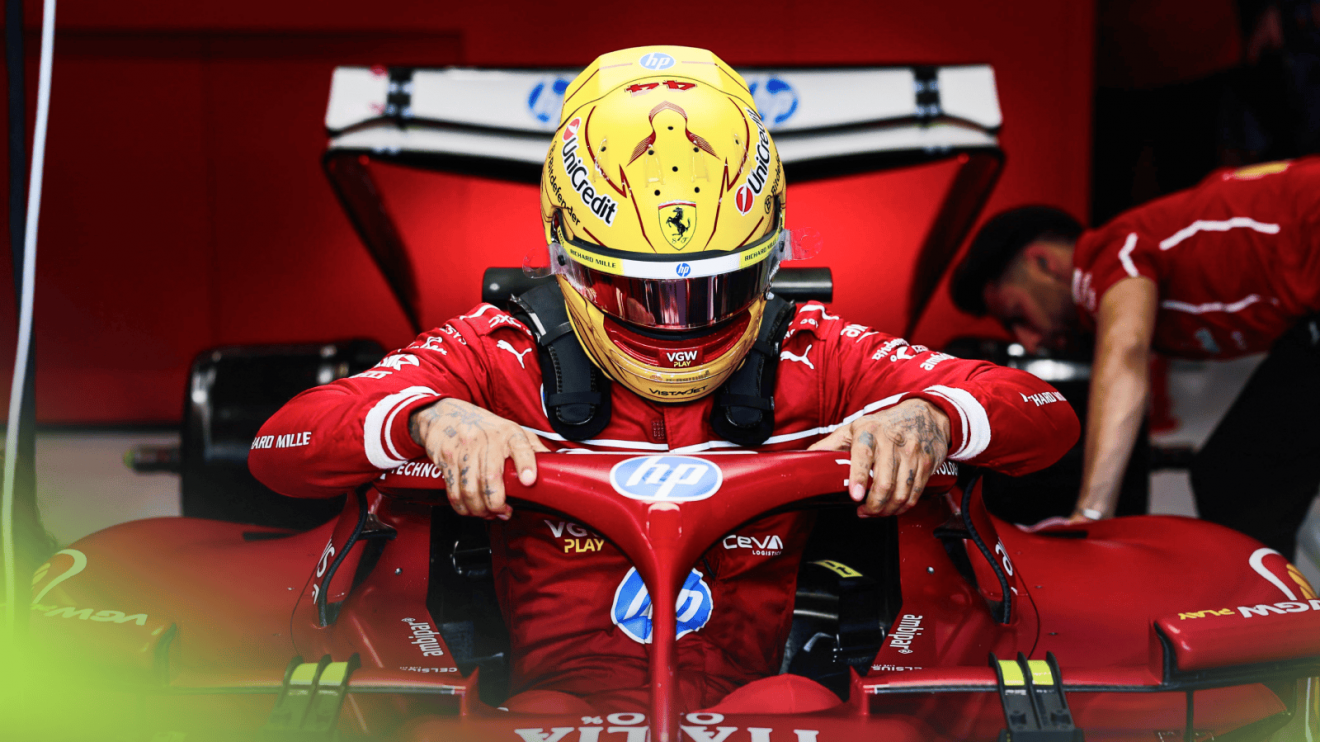 Lewis Hamilton holds on to the halo as he lowers himself into the SF-25 in the Ferrari garage