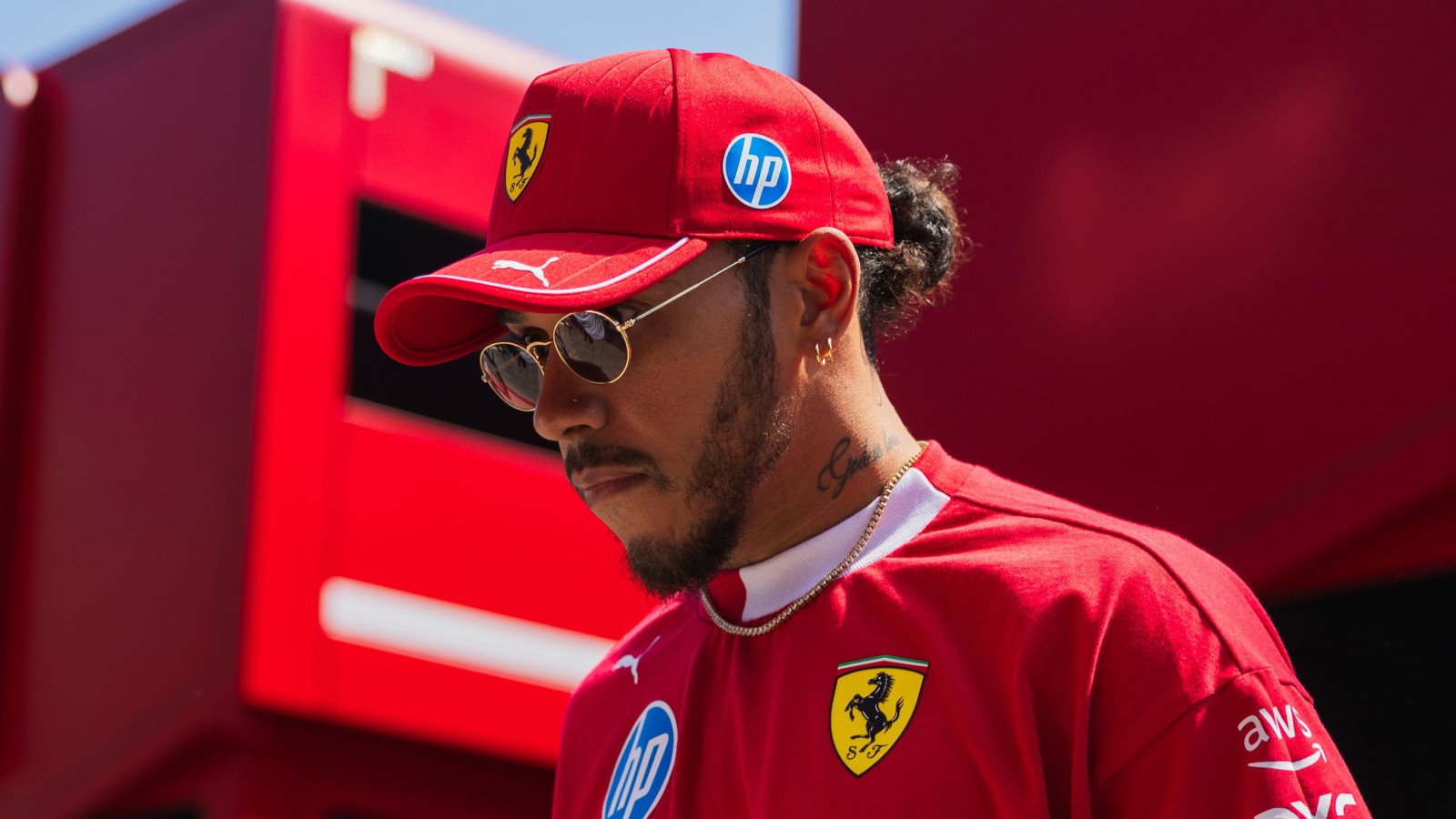 Lewis Hamilton wearing a Ferrari cap and sunglasses in the Imola paddock.