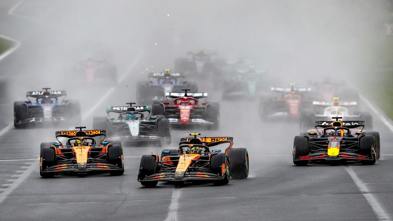 Lando Norris leads the pack as it races towards Turn 1 in the rain at Albert Park at the start of the 2025 Australian Grand Prix.