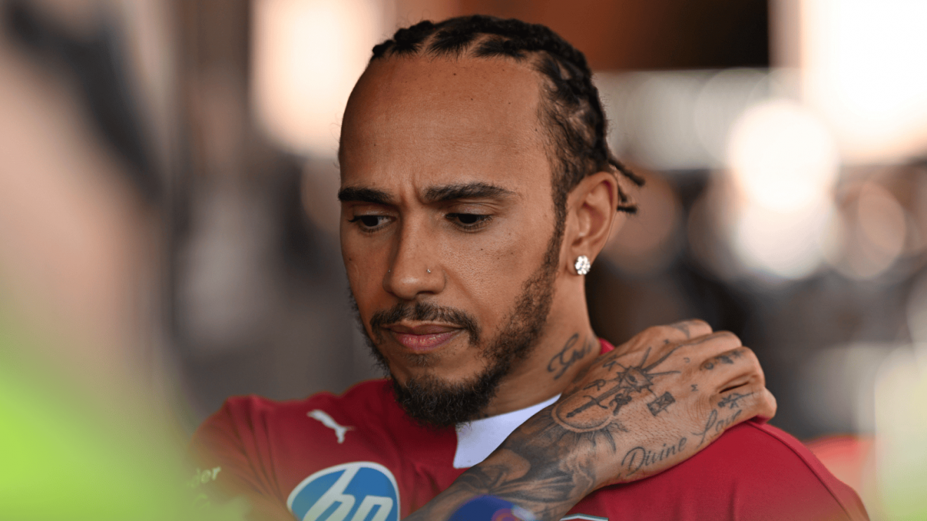 Lewis Hamilton grasps his shoulder as he looks to the floor in Monaco