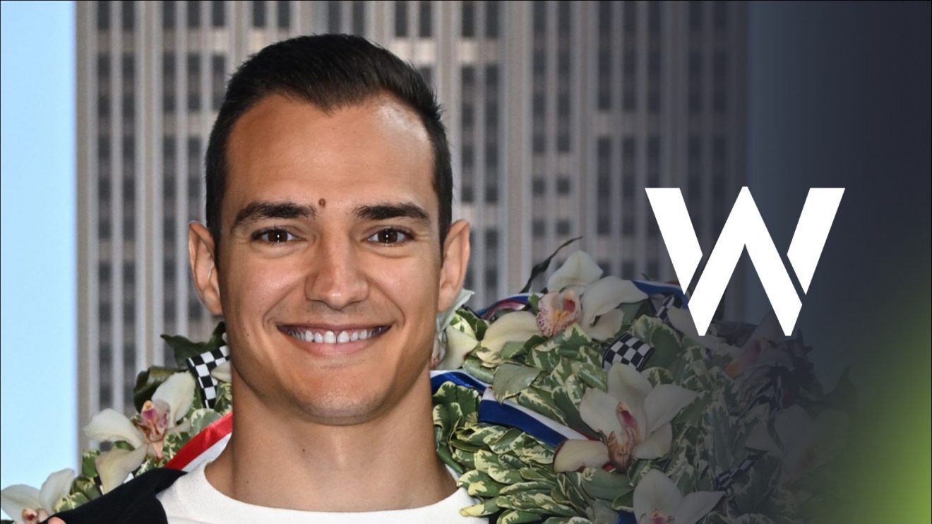 Alex Palou poses after winning the 2025 Indy 500, with a Williams badge on his right