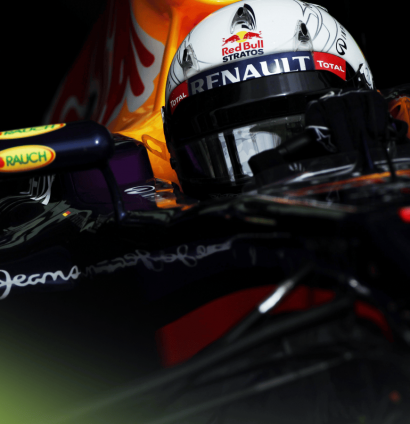 A dramatic shot of Sebastian Vettel wearing a special tribute helmet to Felix Baumgartner behind the wheel of the Red Bull RB9 in 2013