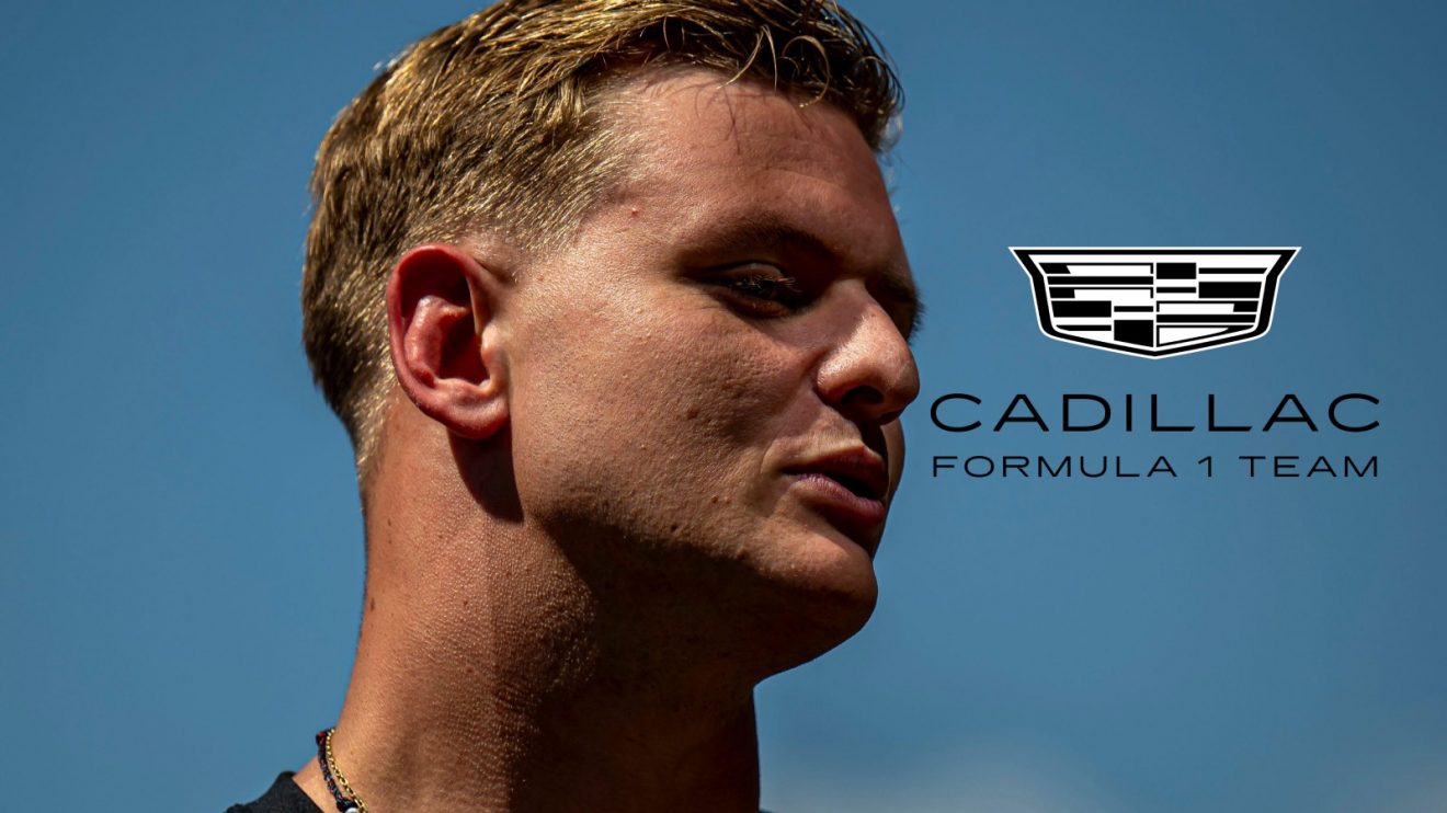 Former Haas F1 driver Mick Schumacher pictured at the 2025 Austrian Grand Prix, looking towards a Cadillac F1 badge on his right