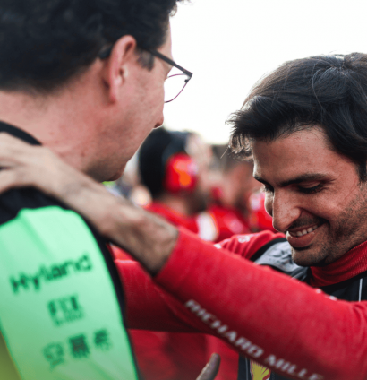 Carlos Sainz smiles as he greets Mattia Binotto on the grid at Abu Dhabi 2024
