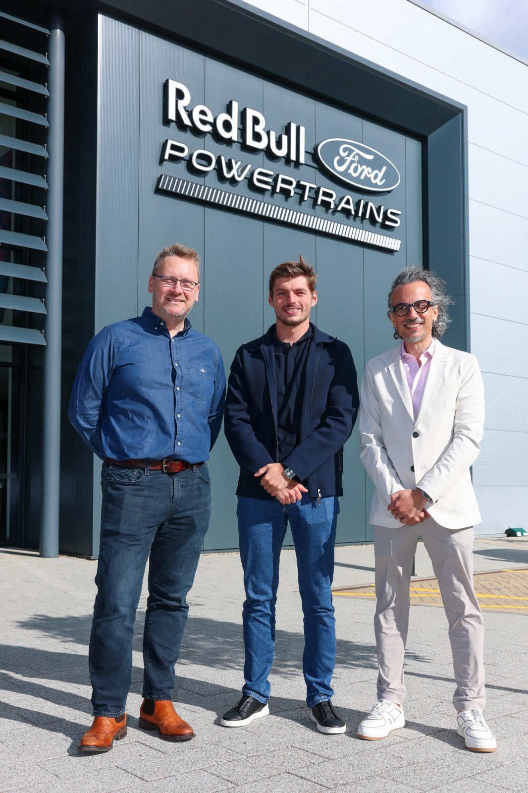 Max Verstappen, Ben Hodgkinson, and Laurent Mekies outside the Red Bull Powertrains facility at Milton Keynes.