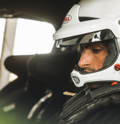 Carlos Sainz wearing a plain-white helmet in the cockpit of the Ford Raptor T1+ car
