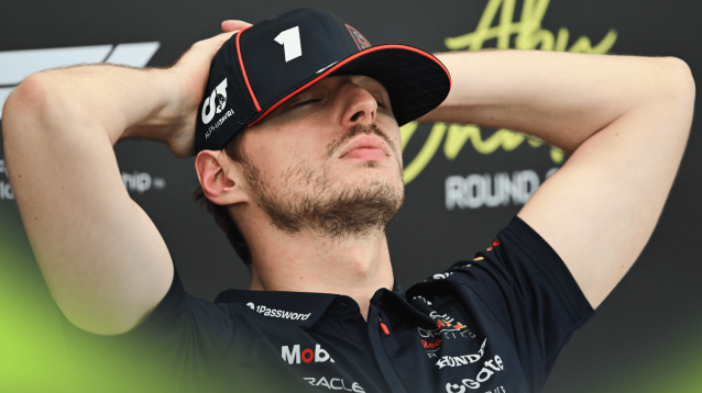 Max Verstappen sits with his eyes closed and his hands at the back of his head in a press conference in Abu Dhabi