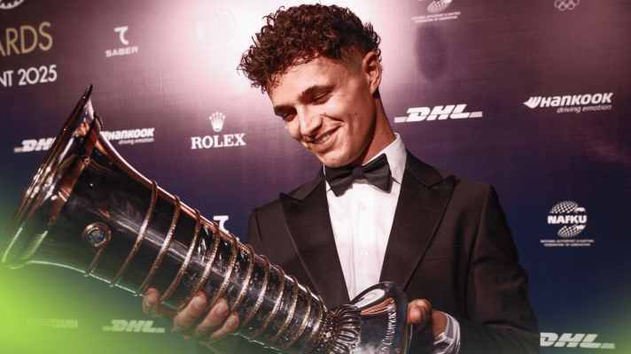 Lando Norris smiles as he studies the F1 world championship trophy at the FIA prize-giving gala
